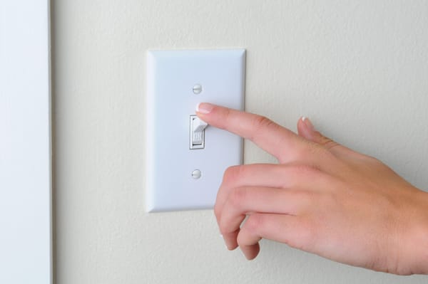 Hand turning light switch to "off" position
